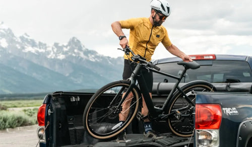 Un uomo sta mettendo una bici elettrica Fiido C21 nel pianale di un camion