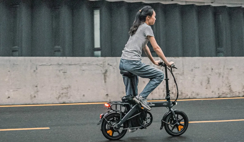 Donna che guida una bicicletta elettrica Fiido D3 Pro attraverso l'acqua.