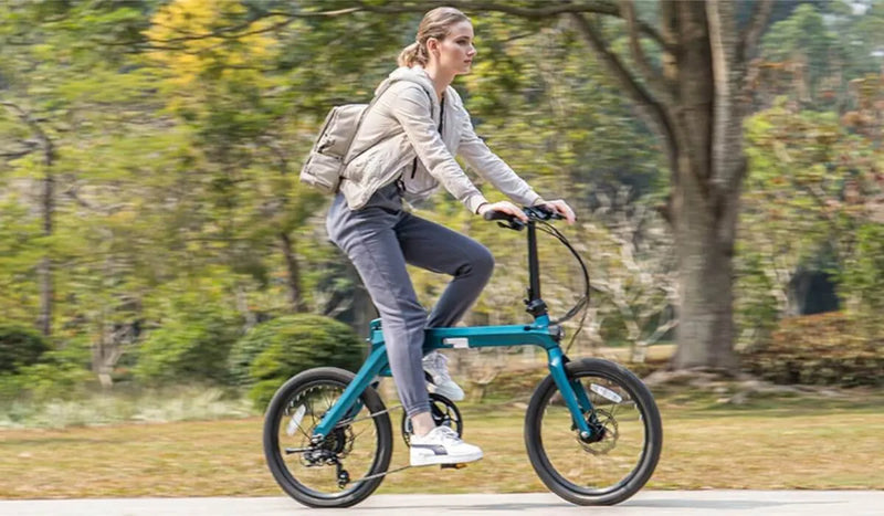 Una donna percorre un parco lussureggiante su una bicicletta elettrica Fiido X.