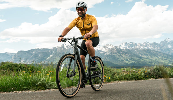 Un uomo pedala sulla sua bici elettrica Fiido C21 in mezzo a uno scenario montano.