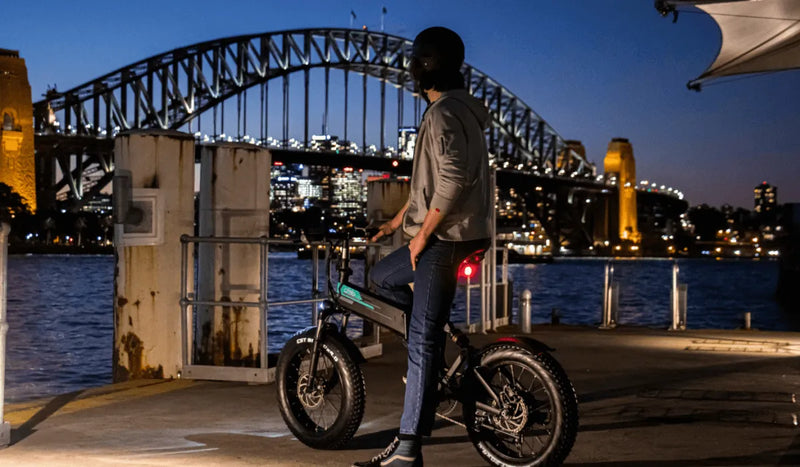 Un uomo con il casco guida la Fiido M1 Pro E-Bike di notte in città.