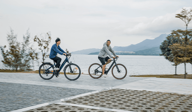 Due uomini in sella alle bici elettriche Fiido C11 in riva al lago