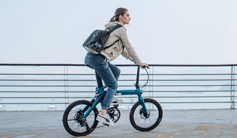 Donna in sella alla bici elettrica Fiido X su una passerella.