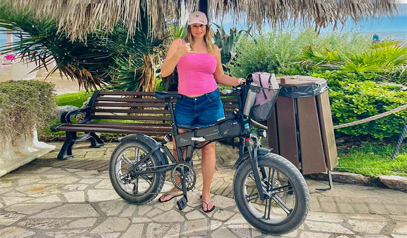 Eleonora è in piedi accanto a una bici elettrica Fiido M1 Pro con una panchina e del verde sullo sfondo.