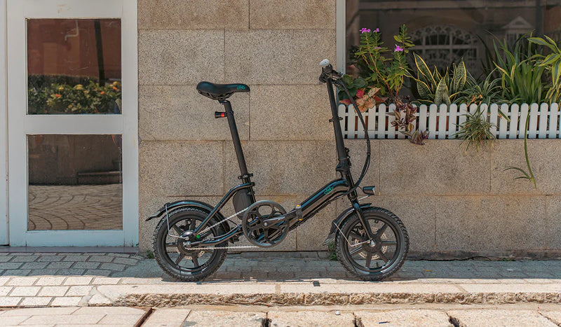 La bicicletta elettrica Fiido D3pro è appoggiata accanto al muro.