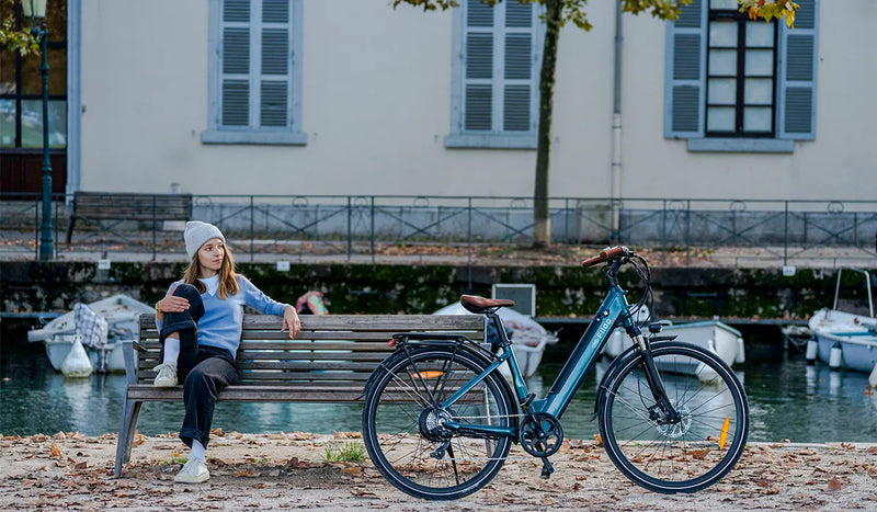 Una donna seduta su una panchina del parco guarda la bici elettrica Fiido C11pro