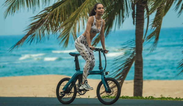 Una donna in forma pedala su una bici elettrica fiido D11 sulla spiaggia.