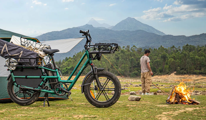 Bici elettrica cargo Fiido T2 carica di attrezzatura da campeggio in un campeggio di montagna, accanto a una tenda e a un falò
